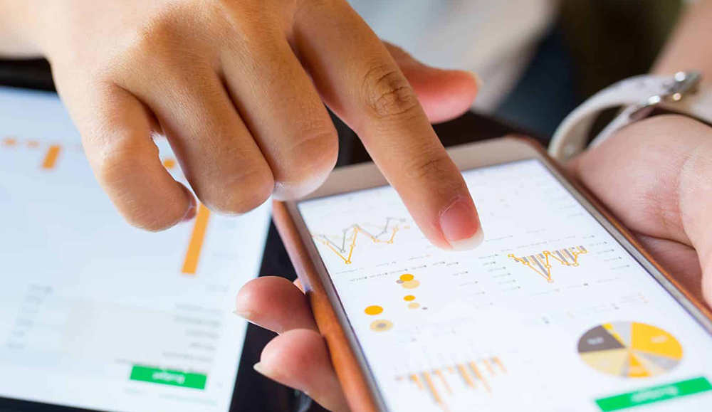 En kvinnelig hånd som trykker på noen grafer på mobilen.