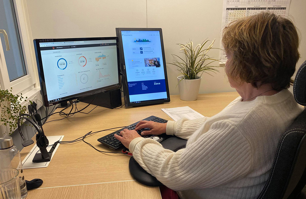 En regnskapsmedarbeider som sitter på kontoret sitt og bruker programmet Poweroffice på PC'en sin.