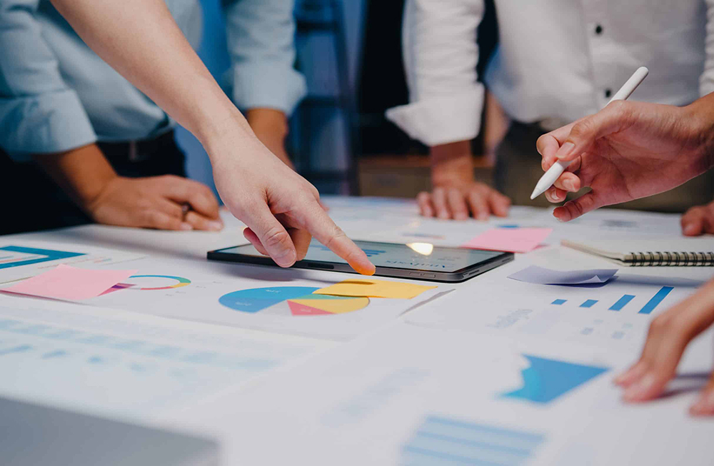 Kollegaer innen regnskap som står bøyd over bordet og diskuterer tall.